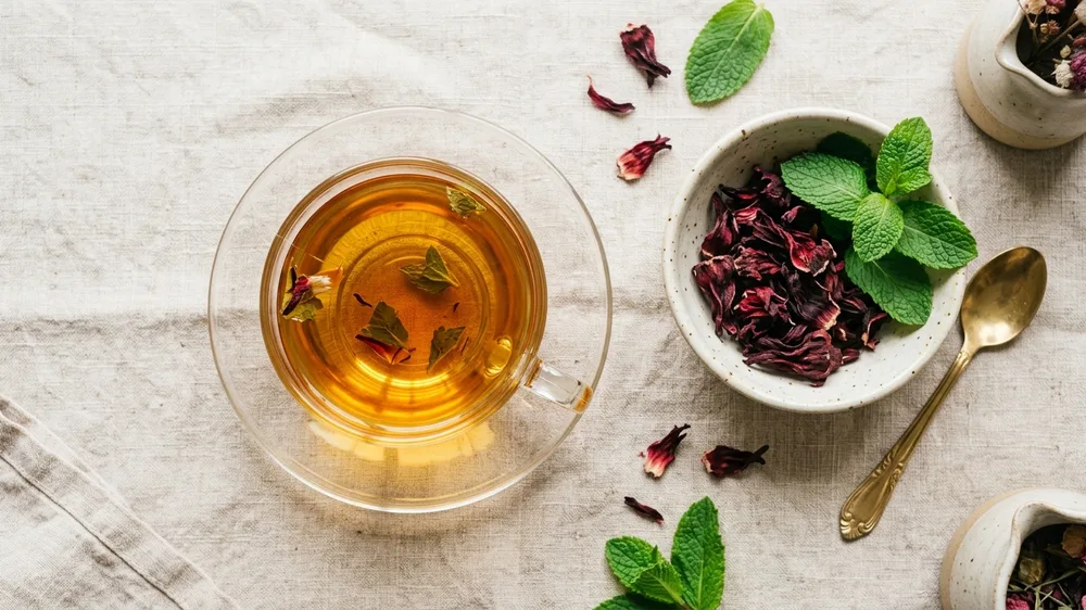 Xícara de chá de ervas diuréticas com hibisco e folhas de hortelã fresca para desinchar
